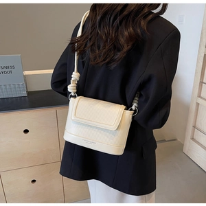 Detail showing vertical textured pattern and knot design on ivory shoulder bag