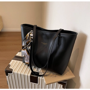Detail of black leather tote bag with fashion gold lettering and silk scarf decoration