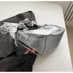 Gros plan d'un sac à bandoulière argenté plissé avec finition métallique et détails zippés