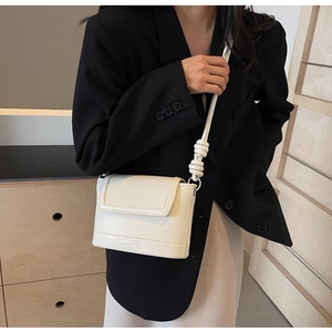 Detail of cream crossbody bag with vertical texture and decorative knot shoulder strap