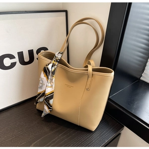 Detail of khaki leather tote bag with embossed fashion logo and decorative silk scarf