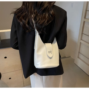 Chic cream white hobo bag with metal bow detail shown on model for size perspective