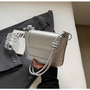 Detail of silver vertical striped leather crossbody bag with knot strap and brand logo