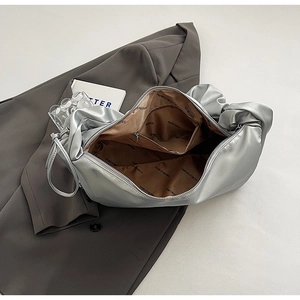 Détail du sac plissé argenté montrant la doublure avec logo et la poche intérieure zippée