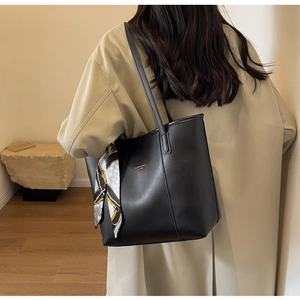 Detail of black leather tote bag with elegant silk scarf on shoulder strap