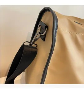 Detail of khaki travel bag showing gun-metal D-ring and black woven shoulder strap