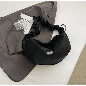 Détail du sac plissé noir avec large bandoulière nuage et plaque logo argentée
