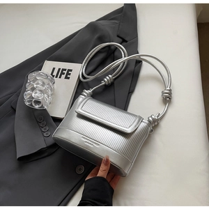 Detail view of silver textured PU leather flap bag with vertical stripes and knotted strap
