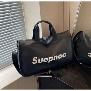Macro shot of waterproof black travel bag showing large white lettering and metal strap hooks