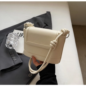 Detail showing cream pleated leather texture and knot shoulder strap on square bag