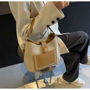 Detail of beige shoulder bag with brown pocket and stylish white contrast stitching