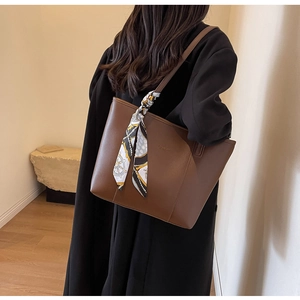 Close-up of brown leather tote bag featuring a geometric silk scarf on the shoulder strap