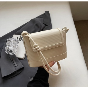 Detail of cream pleated crossbody bag with a knot-style strap and embossed logo