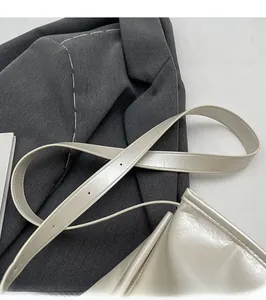 Détail de la bandoulière réglable sur le sac oreiller crème avec finition brillante