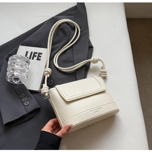 Detail of cream white crossbody bag with vertical texture and knotted rope strap design