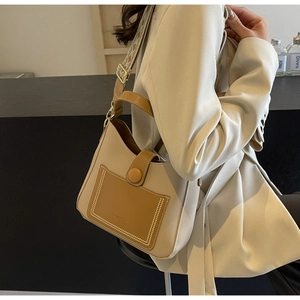 Detail of a beige bucket bag with caramel trim and a vintage geometric patterned strap
