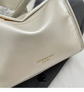 Gros plan du sac oreiller en cuir blanc crème brillant avec gaufrage doré