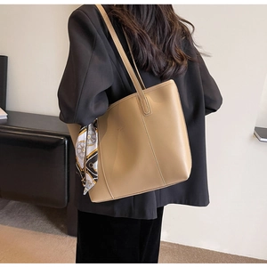Close-up of khaki faux leather tote bag with geometric silk scarf and gold logo detail