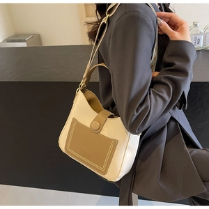 Detailed view of beige and brown hobo bag with textured leather pocket and strap