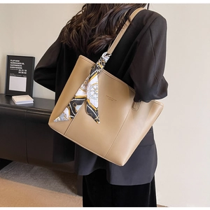 Detail of camel leather tote bag with elegant nautical silk scarf and brand lettering