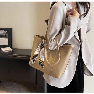 Detail of large beige tote bag with decorative silk scarf and embossed text detail