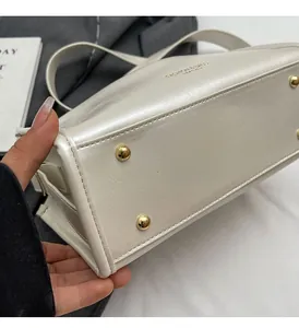 Détails du sac en cuir crème avec rivets de protection dorés et gravure de marque