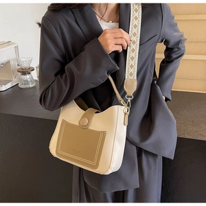 Detail of hobo bag with ethnic woven strap and brown front pocket on beige leather