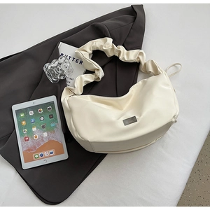Détail du sac à bandoulière plissé blanc crème avec bandoulière nuage sur blazer