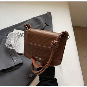Close-up of brown ribbed leather crossbody bag with knot strap and metallic rings