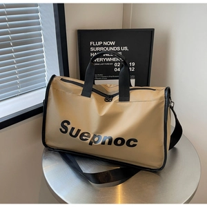 Close-up of khaki travel duffel bag with black straps on a metallic surface