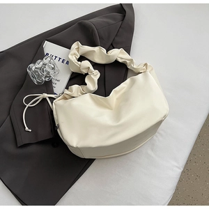 Détail du sac à bandoulière blanc crème plissé en similicuir souple sur veste