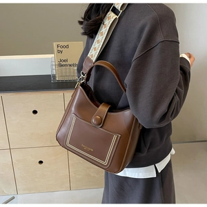 Detail of dark brown leather bucket bag with bohemian embroidery wide shoulder strap