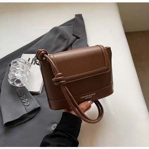 Detail of brown crossbody bag with vertical stripe embossing and fashion logo