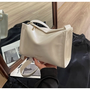 Vue détaillée du sac à bandoulière en cuir beige avec fermeture éclair dorée et logo