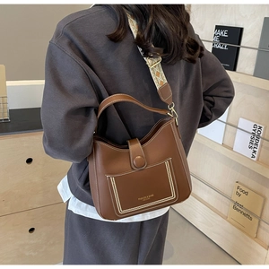 Detail of tan leather shoulder bag with adjustable geometric pattern strap and magnetic flap