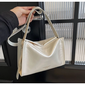 Détail du sac à bandoulière en cuir brillant blanc crème avec fermeture éclair et logo