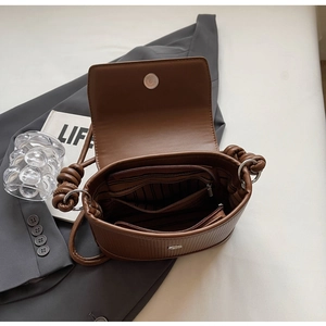 Interior detail of vintage brown crossbody bag showing zip pockets and striped lining