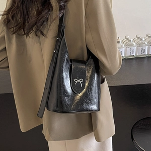 Fashionable black patent leather bucket bag with silver bow buckle and rivet strap