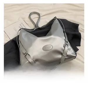 Dettaglio della borsa tote argento con cinturini laterali e logo su ecopelle