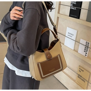 Detailed view of vintage two-tone leather bucket bag worn by model in warm setting
