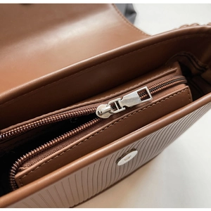 Detail view of brown leather bag showing internal structure and golden metal zipper