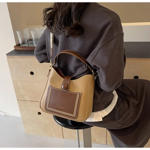 Detail of contrast stitching and leather logo on a brown vintage crossbody bucket bag