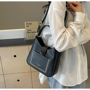 Detail of black leather bucket bag with white stitching and jacquard geometric strap