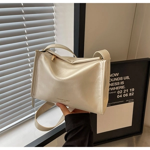 Détail du sac polochon en cuir brillant crème avec texture plissée et zip doré élégant