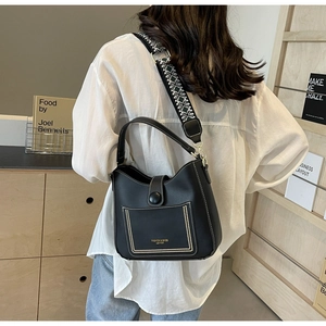 Detail of black leather bucket bag featuring white contrast stitching and a patterned strap