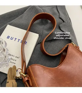 Detail of adjustable wide shoulder strap on vintage brown bucket bag with gold hardware