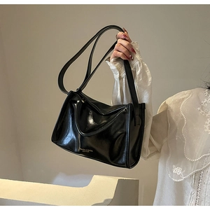 Détail du sac cabas en cuir noir brillant avec lettrage doré et gousset latéral large