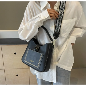 Detailed view of black matte leather bucket bag with patterned strap and rivet decor