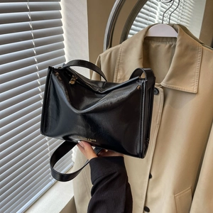 Détail du sac polochon en cuir ciré noir avec fermeture éclair dorée et texture gaufrée