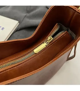 Close-up of golden metal zipper on vintage brown leather bucket bag with premium finish